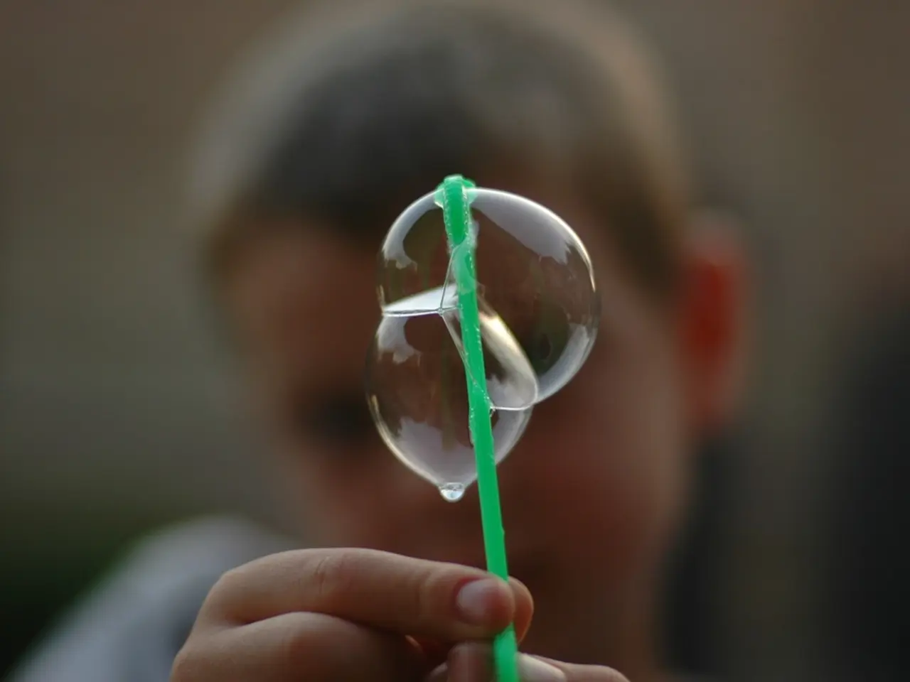 In this image there is a boy holding a straw with a bubbles in the center.