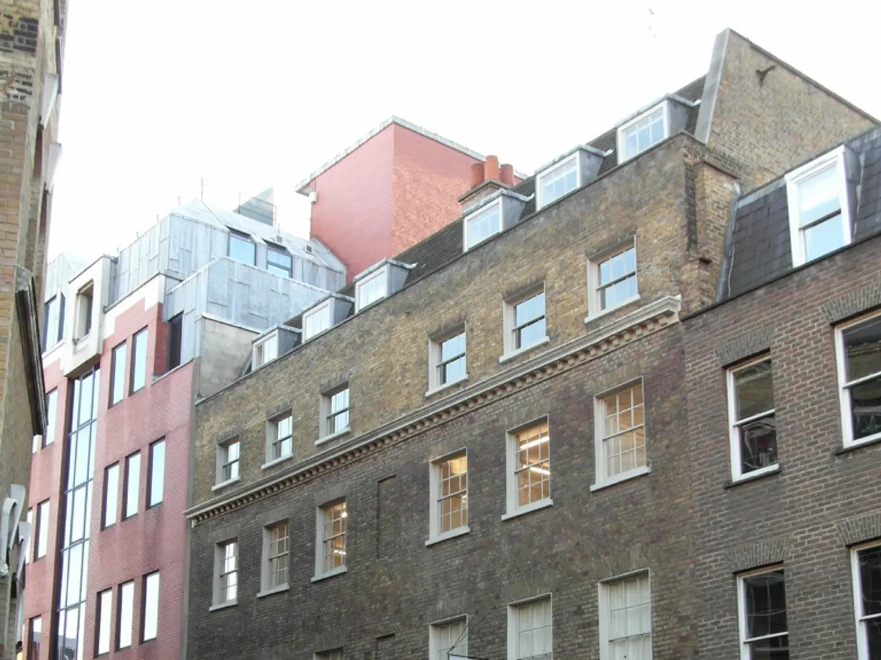 In this image I see the buildings and I see the footpath, road on which there are yellow lines and...