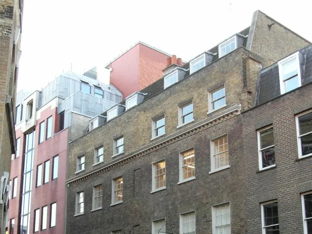 In this image I see the buildings and I see the footpath, road on which there are yellow lines and...